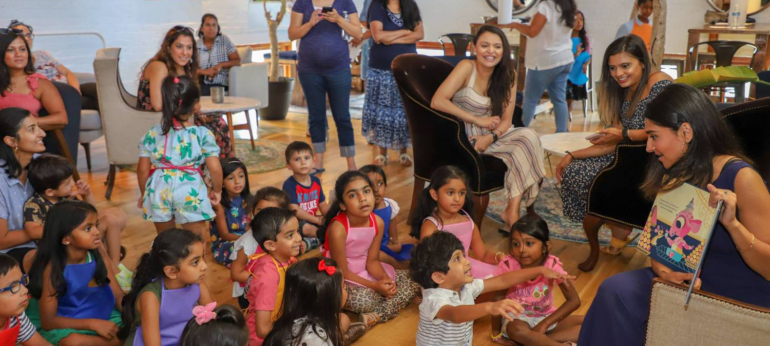 woman reading childrens book to audience of kids and moms