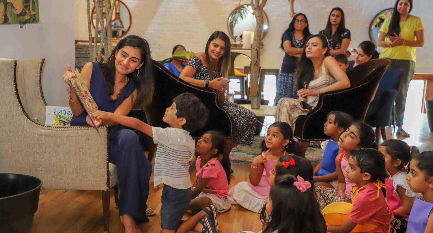 woman reading childrens book to audience of kids and moms